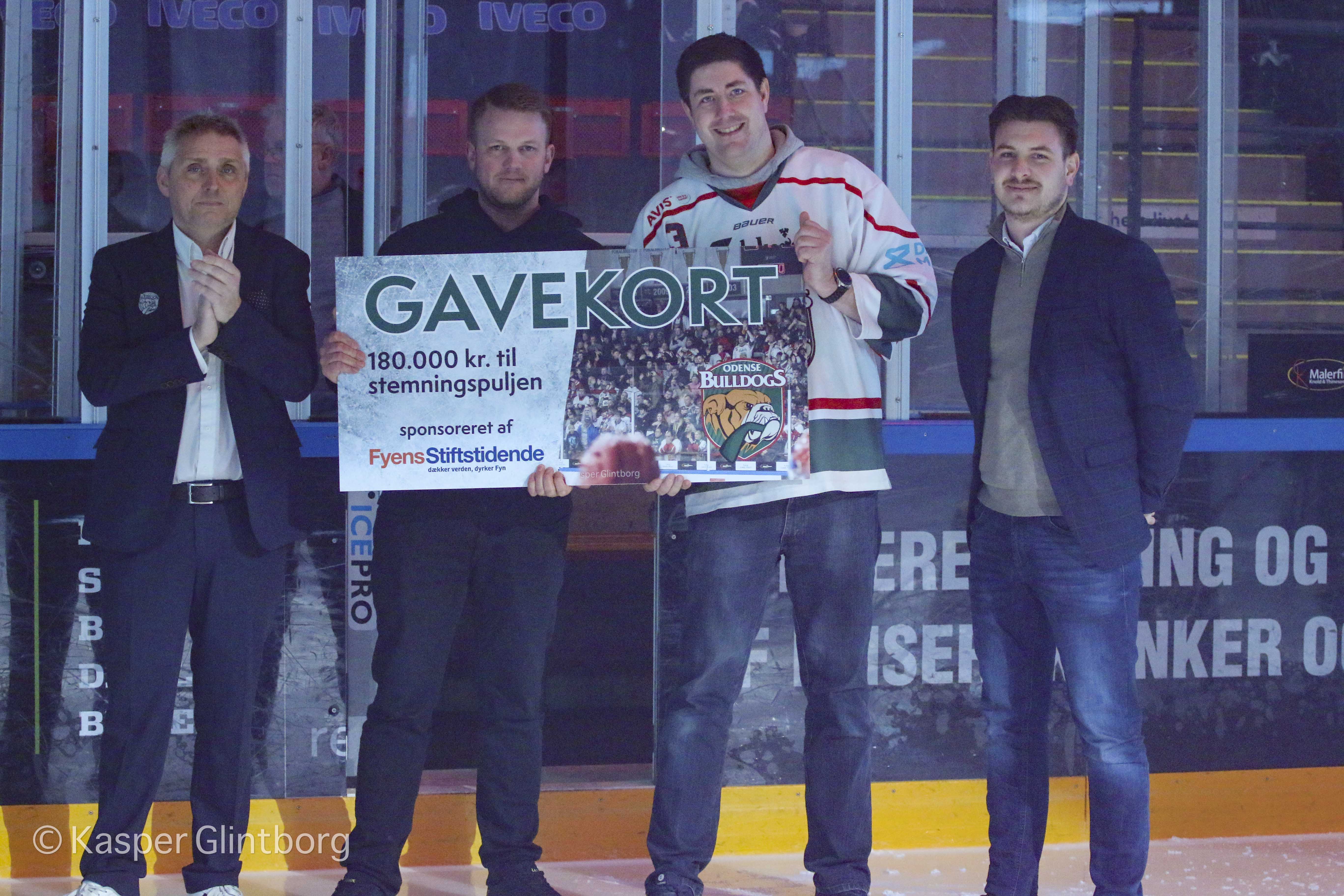 Gavekort på 180.000 kr. til stemningsskabende aktiviteter overrækkes af Mads Juncher fra JFM. Fra venstre: Jacob Landtved (Odense Bulldogs) , Nicolai Mark Zerny (Topdogs), Nicolaj Hansen (Odense Bulldogs Support), Mads Juncher (JFM).